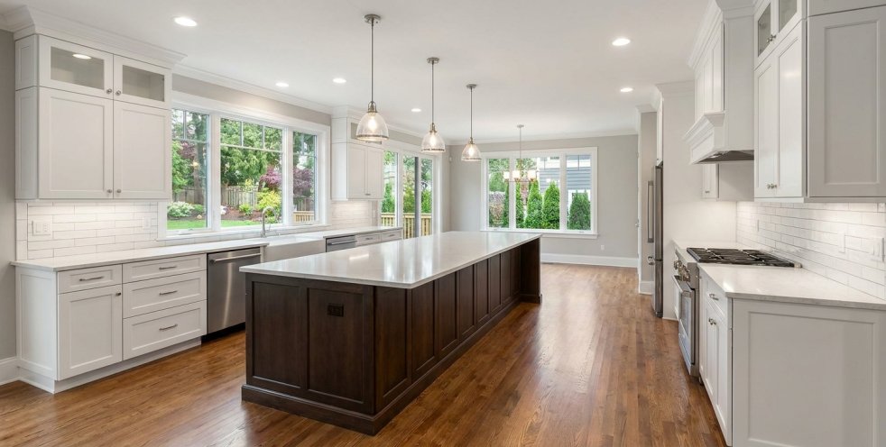 Modern remodeled kitchen with large island, white cabinets, hardwood floors, and pendant lights